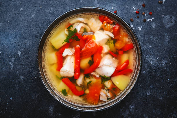 istock Fish soup with cod, paprika, potatoes, tomatoes and parsley in ceramic soup bowl on dark table background, top view 1457826080