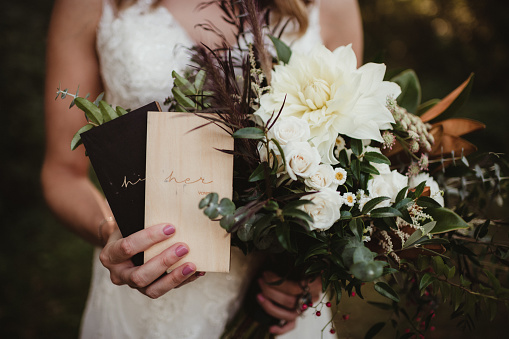 Bride holding flowers and his and hers vow books at a wedding