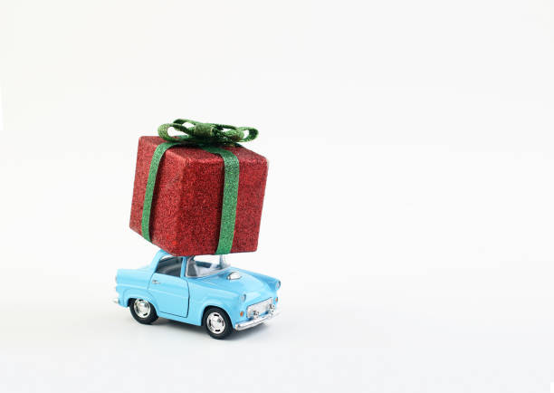 Toy car delivers a gift box for a holiday on a white background.