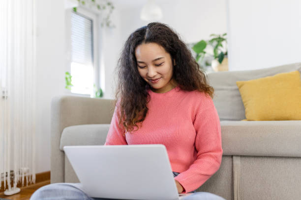 istock Asian woman sitting with computer on sofa, studying at home, e-learning and remote freelance job concept 1457832584