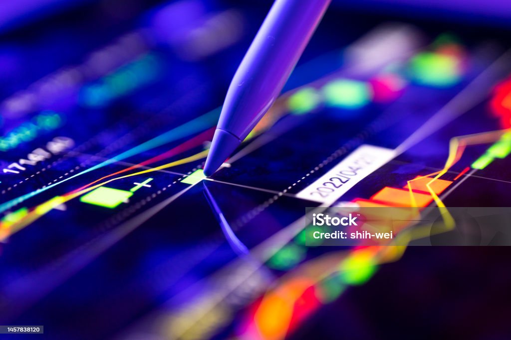 A business person tracking the technical movement of a stock chart on a computer screen. Person analyzing the market trends on a digital screen Technology Stock Photo