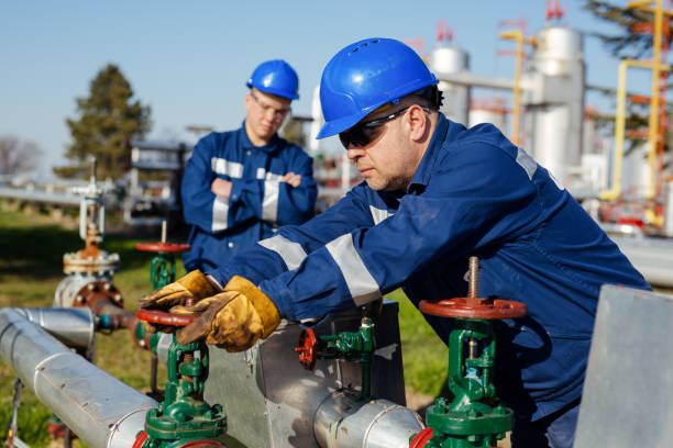 Oil worker turning valve on oil rig Oil worker turning valve on oil rig oil field stock pictures, royalty-free photos & images
