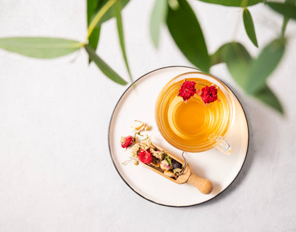 istock Fragrant herbal tea with pomegranate flowers in a glass cup on a plate on a white background with eucalyptus branches. The concept of a healthy drink for breakfast. 1457841802
