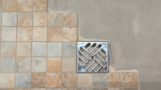 installation of new tiles on floor of Italian shower with evacuation of water diy tiling  work in progress in domestic bathroom