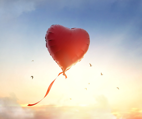 Two red heart-shaped balloons floating in a blue sky with copy space.