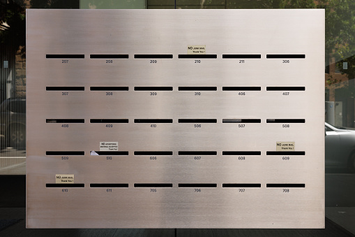 Closeup on a brushed metal wall with numbered mail slots.