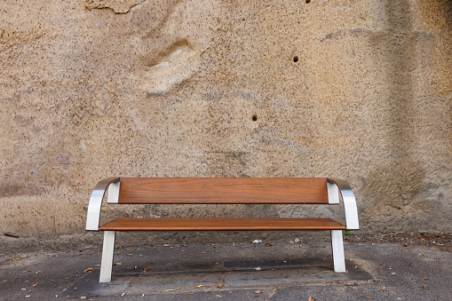 Wooden bench front of a white stone wall