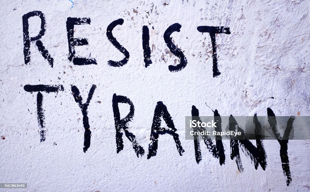Resist Tyranny, says graffiti slogan painted on wall Graffitist urges readers to resist tyranny. Graffiti Stock Photo
