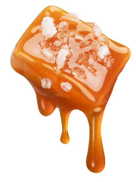 Photo of Salty caramel candy and drops of milk caramel sauce flowing down from it. File contains clipping path.