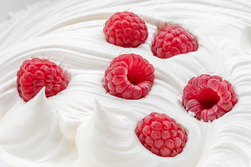 Fresh raspberries in the yoghurt or cream. Top view.