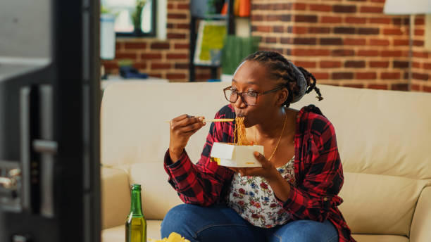 istock Cheerful girl using chopsticks to eat noodles 1457856980