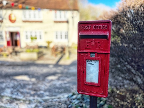 Close up of a red traditional postbox in an English village.