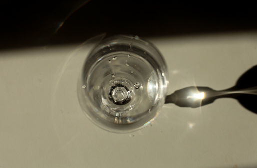 a glass of transparent clear water close-up casts sunbeams on a white table