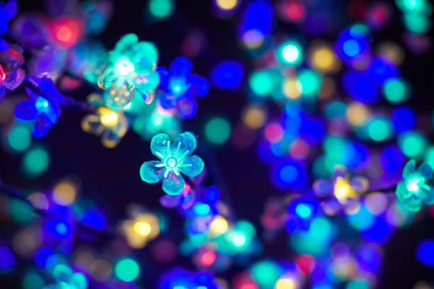 Multicolored lights bokeh from decorative luminous flowers garlands at holiday, blurred festive background, abstract outdoor lights with boke. Colorful flowers lights with beautiful bokeh at night