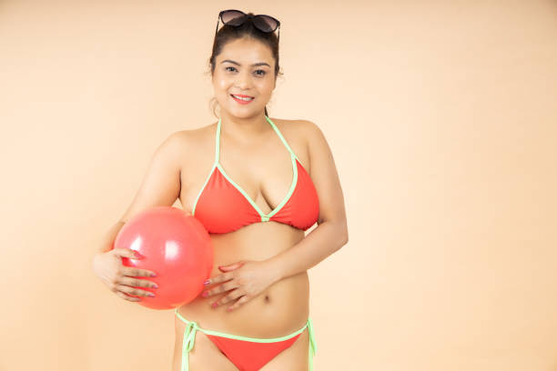 happy young brunette asian woman slim body wearing red bikini hold play beach ball isolated on beige background, studio shot. summer holidays and travel concept. - party beach indian ethnicity adult imagens e fotografias de stock