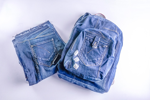 Part of old jeans ready to upcycling and a handmade backpack made of another part. Concept of things reuse and natural resources preserving.