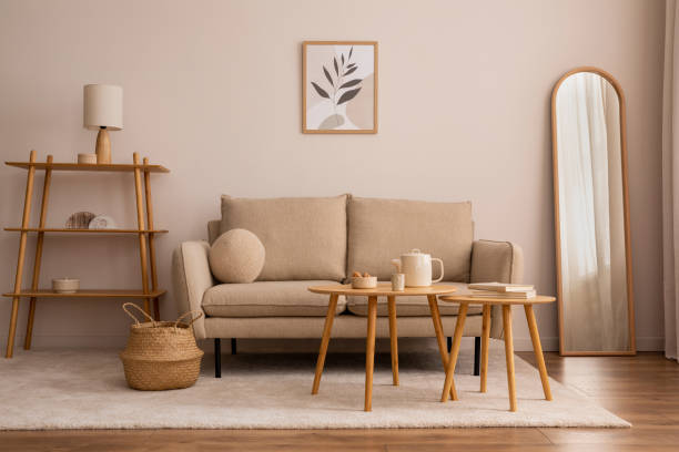 istock Creative composition of living room interior with mock up poster frame, classic design sofa, wooden round coffee table, mirror, basket, round pillow, bright carpet and personal accessories. Home decor. Template. 1457867461