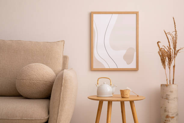 istock Cozy living room interior with mock up poster frame, classic beige sofa, round coffee table, vase with dried flowers, boucle pillow and personal accessories. Home decor. Template. 1457867465