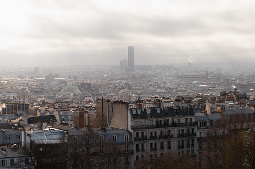 View of Paris on a cloudy foggy day from the Montmartre hill through the roofs of houses - the Eiffel Tower in the fog