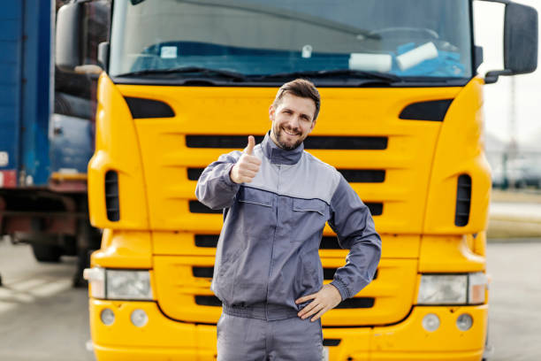 um motorista feliz está dando polegares para cima para o transporte eficiente e no prazo enquanto está na frente do caminhão. - flatbed truck truck truck driver heavy - fotografias e filmes do acervo