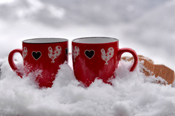 istock two red mugs with heart shaped on the snow and mountain background 1457873253
