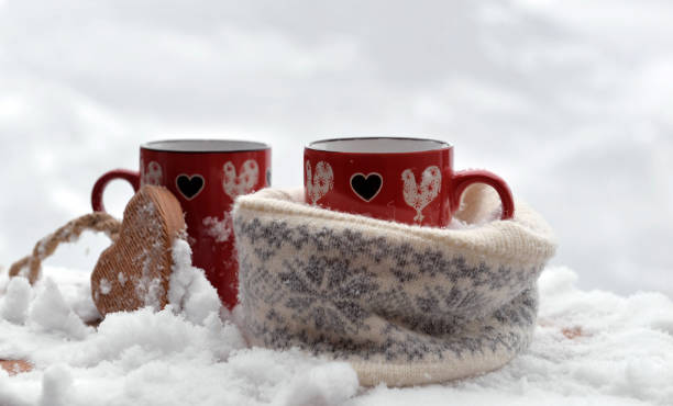 istock two red mugs with heart shaped one in a woolen hat  on the snow 1457873429