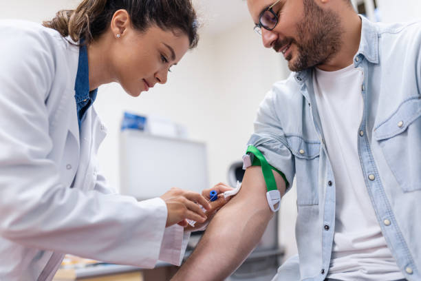 preparazione per l'esame del sangue da parte del medico femminile uniforme medica sul tavolo in camera bianca e luminosa. l'infermiera perfora la vena del braccio del paziente con un tubo bianco con ago. - blood blood sample blood donation tube foto e immagini stock