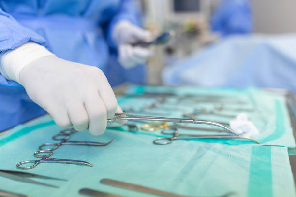 istock Operating Room of Surgical Table with Instruments, Assistant Picks up Instruments for Surgeons During Operation. Surgery in Progress. Professional Medical Doctors Performing Surgery. 1457875292