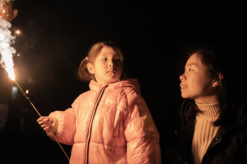 women accompany children to set off fireworks