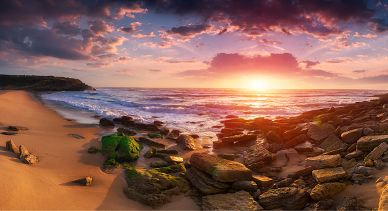 Colorful panoramic landscape of amazing sunset on the Atlantic Ocean. Praia das Macas is the beach with the best scenic views near Sintra. Colares. Portugal. Concept of harmony with wildlife.