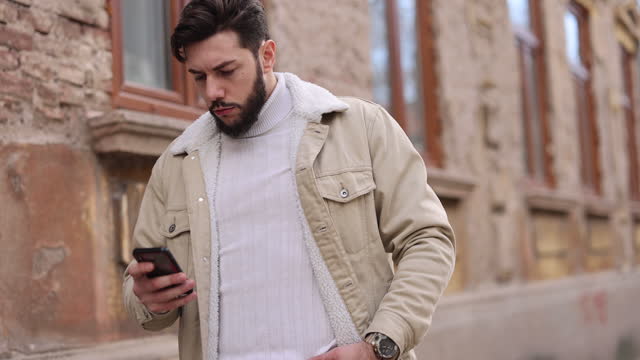 Attractive young man texting while walking in the city