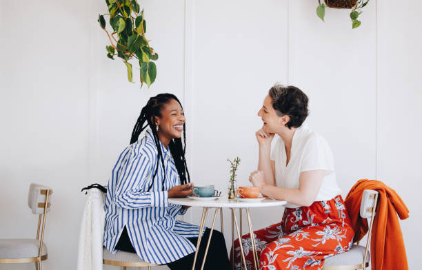 Two happy businesswomen chatting during a coffee break in a cafe Two happy businesswomen chatting and laughing together during a coffee break in a cafe. Cheerful female business colleagues enjoying a friendly conversation in a coffee shop. ladies lunch stock pictures, royalty-free photos & images