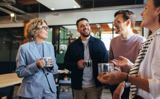 Happy colleagues having a coffee break in an office Happy colleagues having a coffee break in an office. Group of business people having a conversation in a workplace. Business professionals working in a startup. event stock pictures, royalty-free photos & images