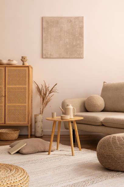 istock Suny and bright interior with beige sofa, round wooden coffee table, brown pouf, rattan commode, pilows and personal accessories. Home decor. Template. 1457879832