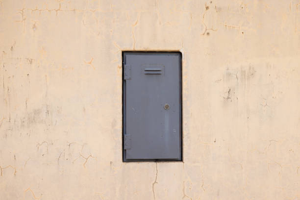 Gray metal door with key hole in a concrete wall.