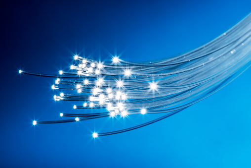 Bundle of optical fibers with lights in the ends. Blue background.