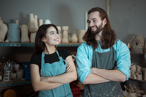 Portrait of Young business man and woman having a little ceramic business, with the pottery business and pottery goods in stock