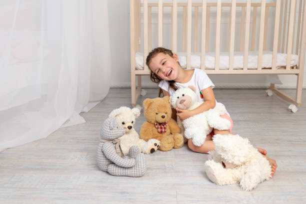 petite fille de 5-6 ans jouant dans la chambre des enfants avec des ours en peluche - 6 7 years photos et images de collection