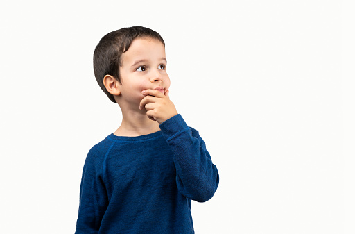 Dark haired little child wearing winter sweater over isolated white background with hand on chin thinking about question, thoughtful expression.Concept of doubt and looking aside