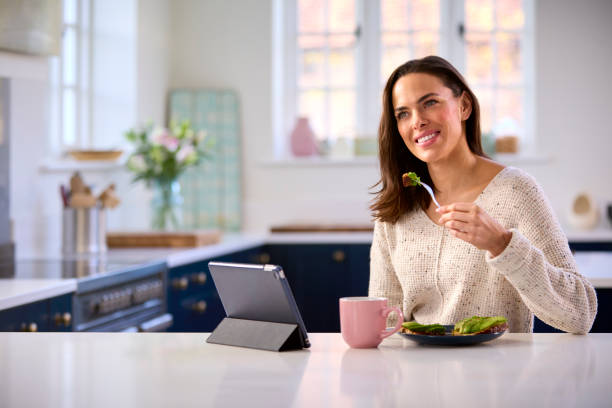 istock Woman At Home With Digital Tablet On Kitchen Counter Eating Lunch 1457891171