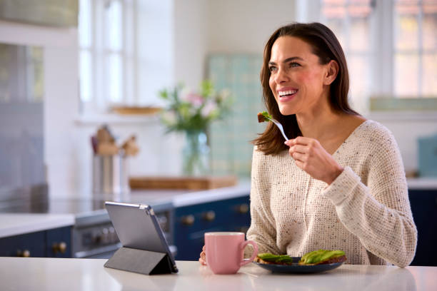 istock Woman At Home With Digital Tablet On Kitchen Counter Eating Lunch 1457891264