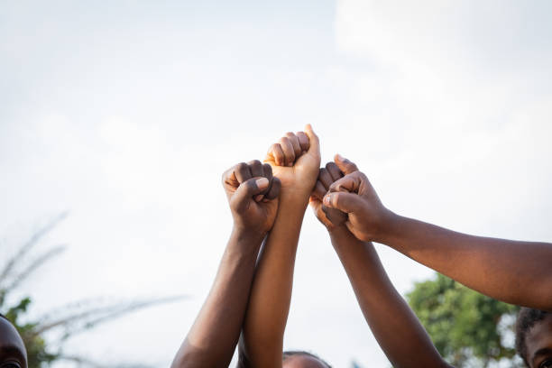 Four fists of African people united in sky, photo with copy space. Four fists of African people united in sky, photo with copy space above alertness stock pictures, royalty-free photos & images
