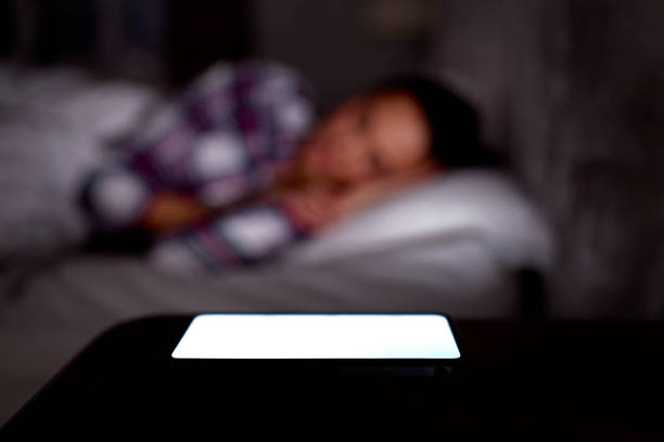 istock Woman Asleep In Bed At Home With Mobile Phone Lit Up On Bedside Table 1457891993