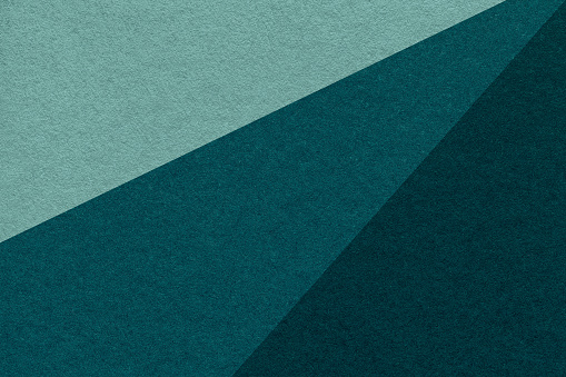 Texture of old craft cyan, emerald and teal color paper background, macro. Vintage abstract green cardboard