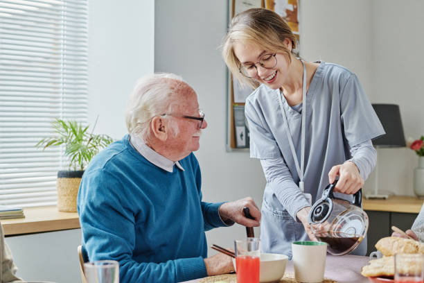 cuidador sirviendo café para hombre mayor - residencia de ancianos fotografías e imágenes de stock