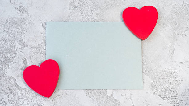 istock Gray paper on gray concrete background and two red hearts 1457907958