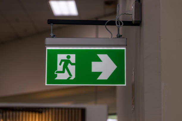 istock Green emergency exit sign showing the way to escape. Fire exit in the building. 1457908323