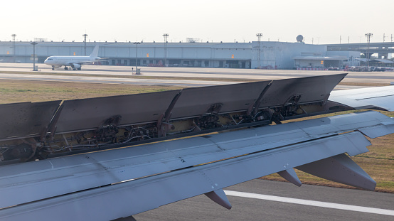 Wing braking of the aircraft on the runway. The wing of an aircraft open flaps on the wing for is landing.