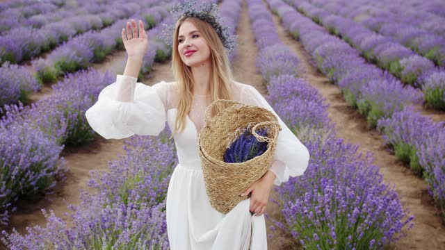 Beautiful girl white dress walks with bouquet of flowers through lavender field