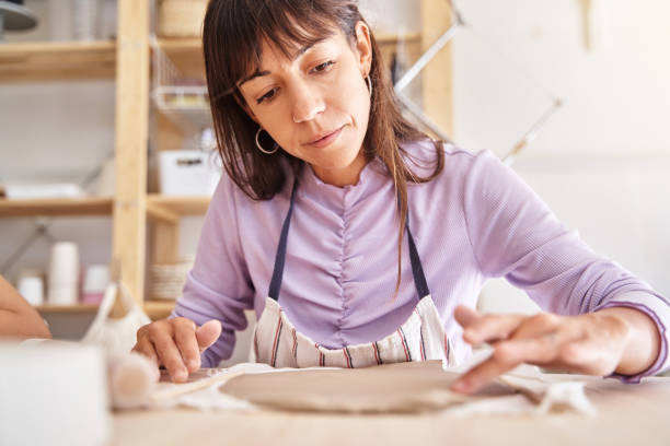 istock Woman potter with apron preparing clay slabs in a pottery workshop. 1457914320